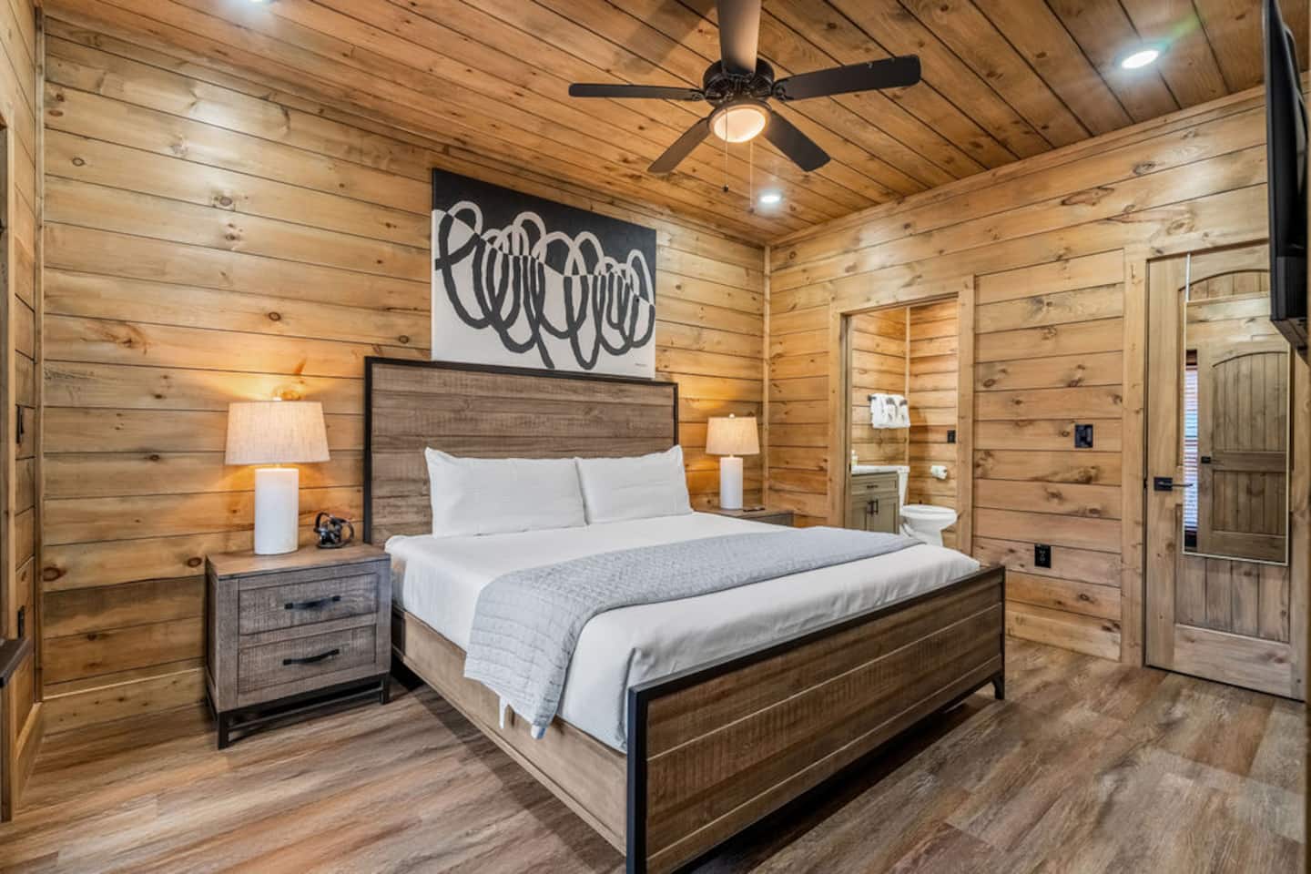 Warm wood-paneled king bedroom with an ensuite bathroom